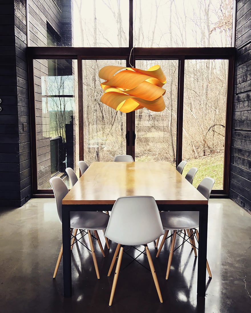 Large dining-table-illuminated-by-a-yellow-wood-veneer-lamp